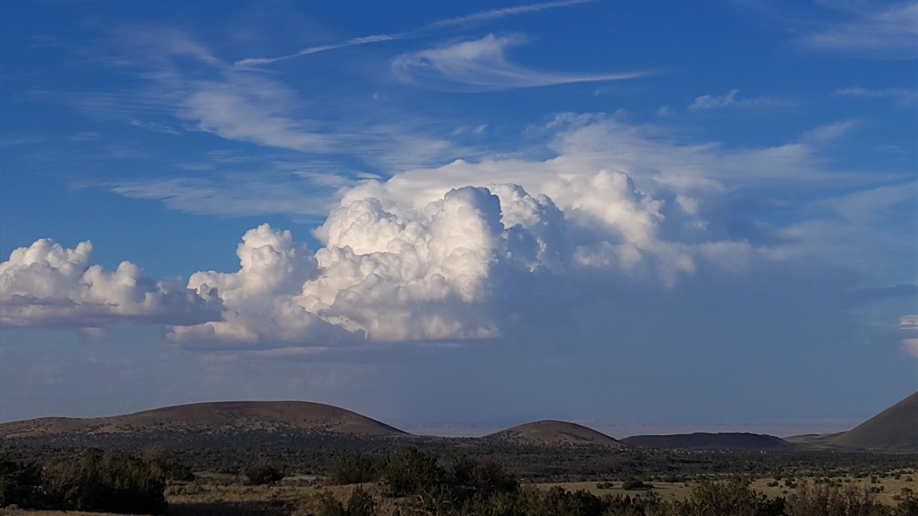 A towering cumulus cloud over the high desert hills